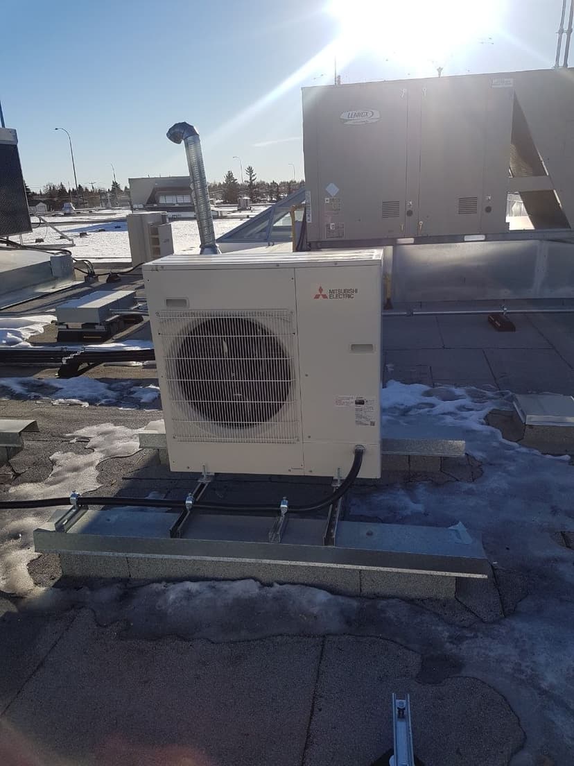 Mitsubishi Electric commercial rooftop condenser unit with snow and ice indicating cold climate operation